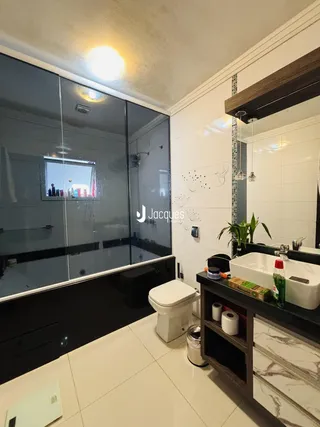 Interior de um banheiro com piso de cerâmica e box de vidro.
