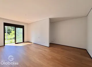 Vista interna de uma sala com piso de madeira e porta de acesso.