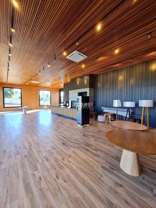 Espaço interno amplo com piso de madeira e teto de madeira.