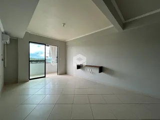 Uma sala de estar ampla com piso de cerâmica clara e porta de vidro.