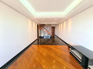 Corredor longo com piso de madeira e escadaria visível.
