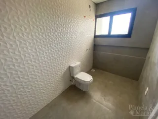 Foto de um banheiro com parede texturizada e vaso sanitário branco.