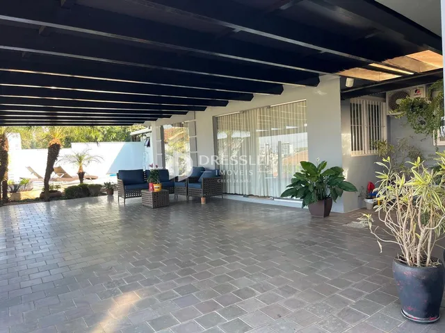 Vista de uma área externa coberta com piso de tijolos e móveis de exterior.