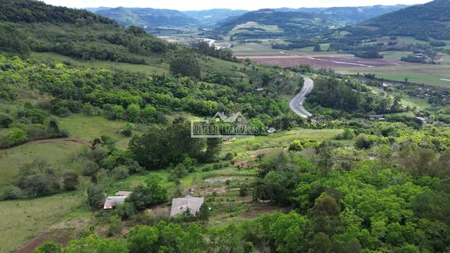 Vista aérea de uma paisagem rural com colinas e vegetação densa.