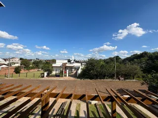 Vista externa de uma propriedade com cerca e jardim sob um céu azul.