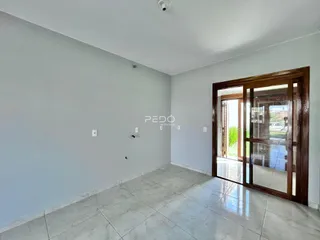 Ambiente interno de uma sala com piso de cerâmica clara e porta de madeira.