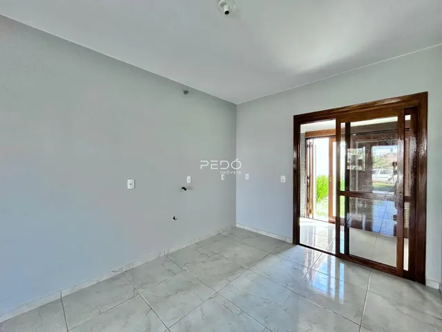 Ambiente interno de uma sala com piso de cerâmica clara e porta de madeira.