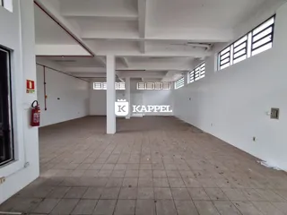 Vista interna de um corredor amplo com piso de cerâmica e janelas laterais.