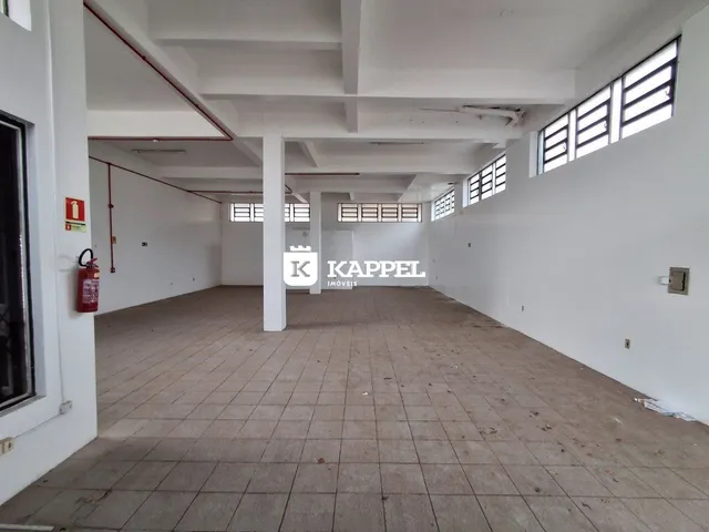 Vista interna de um corredor amplo com piso de cerâmica e janelas laterais.