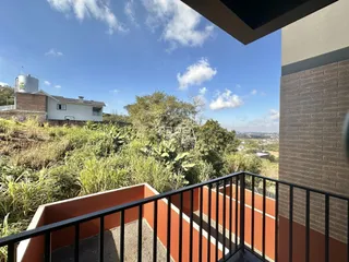 Vista da propriedade com vegetação e paisagem ao fundo.
