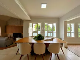 Uma sala de jantar com mesa de madeira e janelas amplas.
