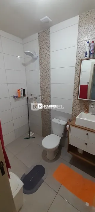 Banheiro com revestimento de azulejos brancos e piso claro.