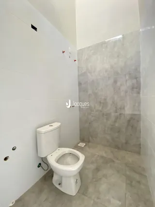 Foto de um banheiro com revestimento branco e cinza.