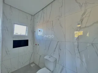 Banheiro com revestimento em mármore branco nas paredes.