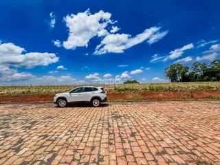 Vista externa da propriedade com um veículo estacionado em uma área pavimentada.