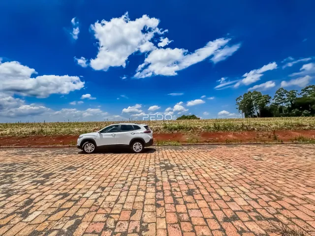 Vista externa da propriedade com um veículo estacionado em uma área pavimentada.