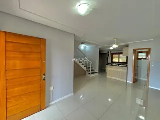Hall de entrada com piso claro e portas de madeira.