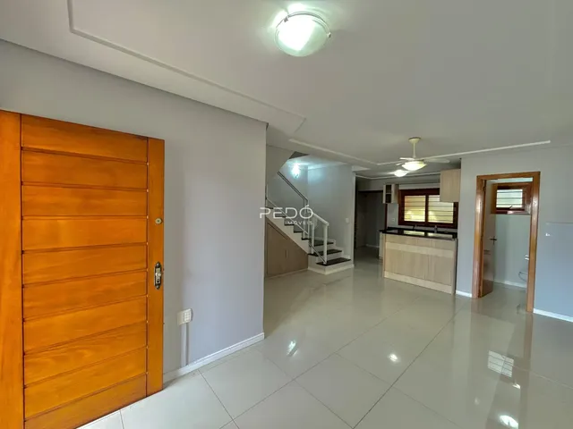 Hall de entrada com piso claro e portas de madeira.