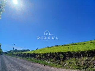 Vista de uma estrada de terra ao lado de uma colina verde no Brasil.