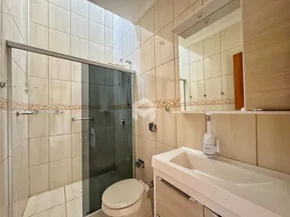Foto de um banheiro com box de vidro e azulejos claros.