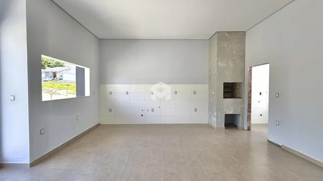 Ambiente interno amplo com paredes brancas e piso de cerâmica.