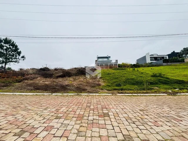Vista externa da propriedade com área pavimentada e vegetação ao fundo.