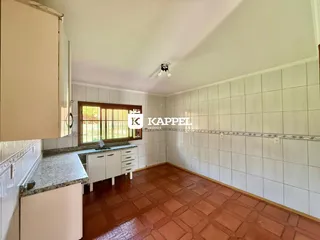 Cozinha com piso de ladrilho avermelhado e paredes brancas.