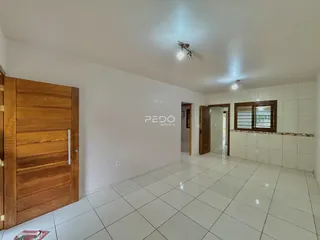 Hall de entrada com piso de cerâmica clara e portas de madeira.