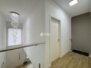 Hall de entrada com piso de madeira clara e parede branca em imóvel no Brasil.