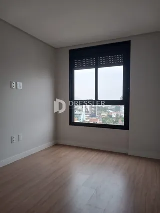 Ambiente interno de uma sala com piso de madeira e janela grande.