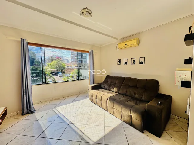 Sala de estar com sofá marrom e piso cerâmico em Lajeado.