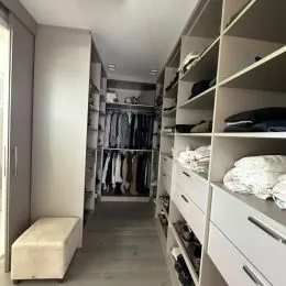 Corredor interno com estantes de armazenamento preenchidas com roupas.