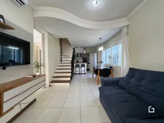 Sala de estar com sofá azul e piso de cerâmica clara.