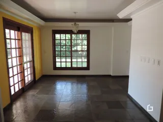 Vista interna de um ambiente com piso de cerâmica escura e portas de madeira.
