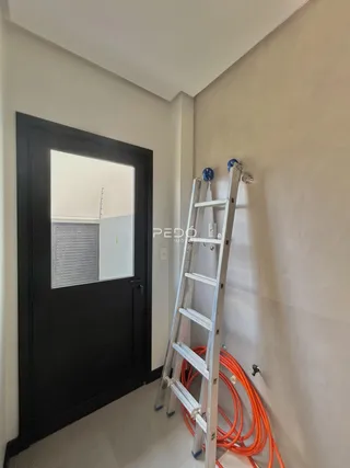 Hall de entrada com porta escura e escada de metal.