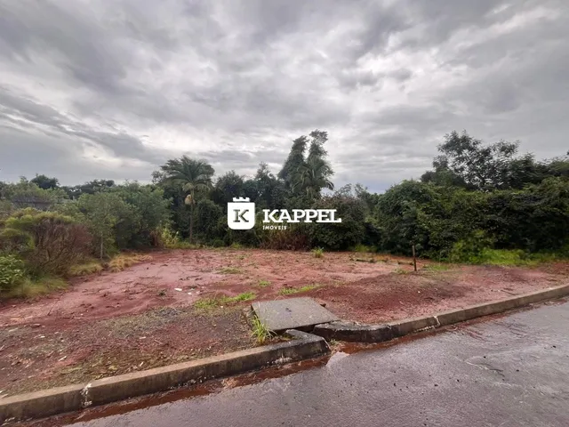 Vista externa de um terreno com vegetação densa e área de terra vermelha.