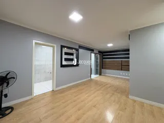 Interior de uma área com piso de madeira clara e paredes cinzas.
