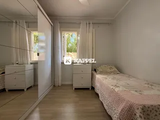 Quarto com cama e móveis brancos.