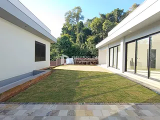 Fachada de uma casa moderna com jardim gramado e vegetação ao fundo.