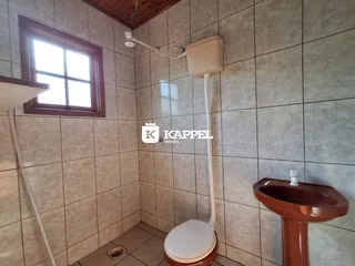 Banheiro com revestimento de azulejos e vaso sanitário branco.