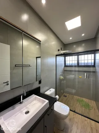 Foto de um banheiro com piso de madeira e box de vidro.