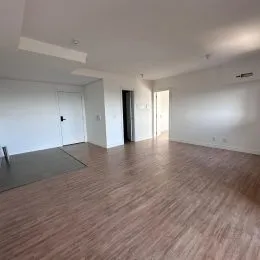 Sala de estar com piso de madeira e paredes brancas.