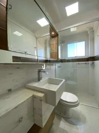 Banheiro moderno com revestimento em mármore e box de vidro.