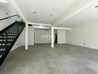 Interior de um espaço amplo com paredes brancas e piso de concreto em uma residência.
