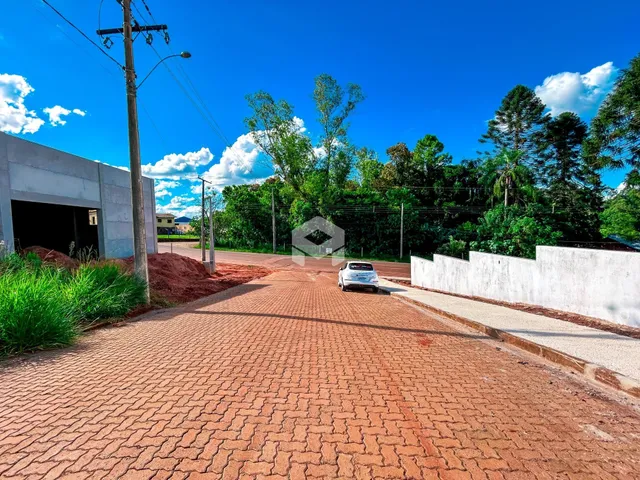 A foto mostra a entrada de uma propriedade com um pátio pavimentado de tijolos.
