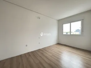 Ambiente interno de uma sala com piso de madeira clara e paredes brancas.