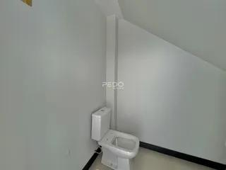 Vista de um corredor interno com um vaso sanitário branco.