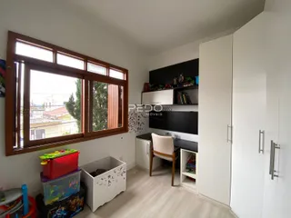 Quarto com grande janela e armários brancos em um imóvel.