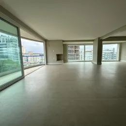 Interior de um ambiente amplo com piso claro e grandes janelas.