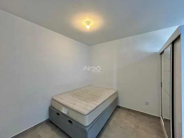 Quarto com cama e paredes brancas em um imóvel no Brasil.